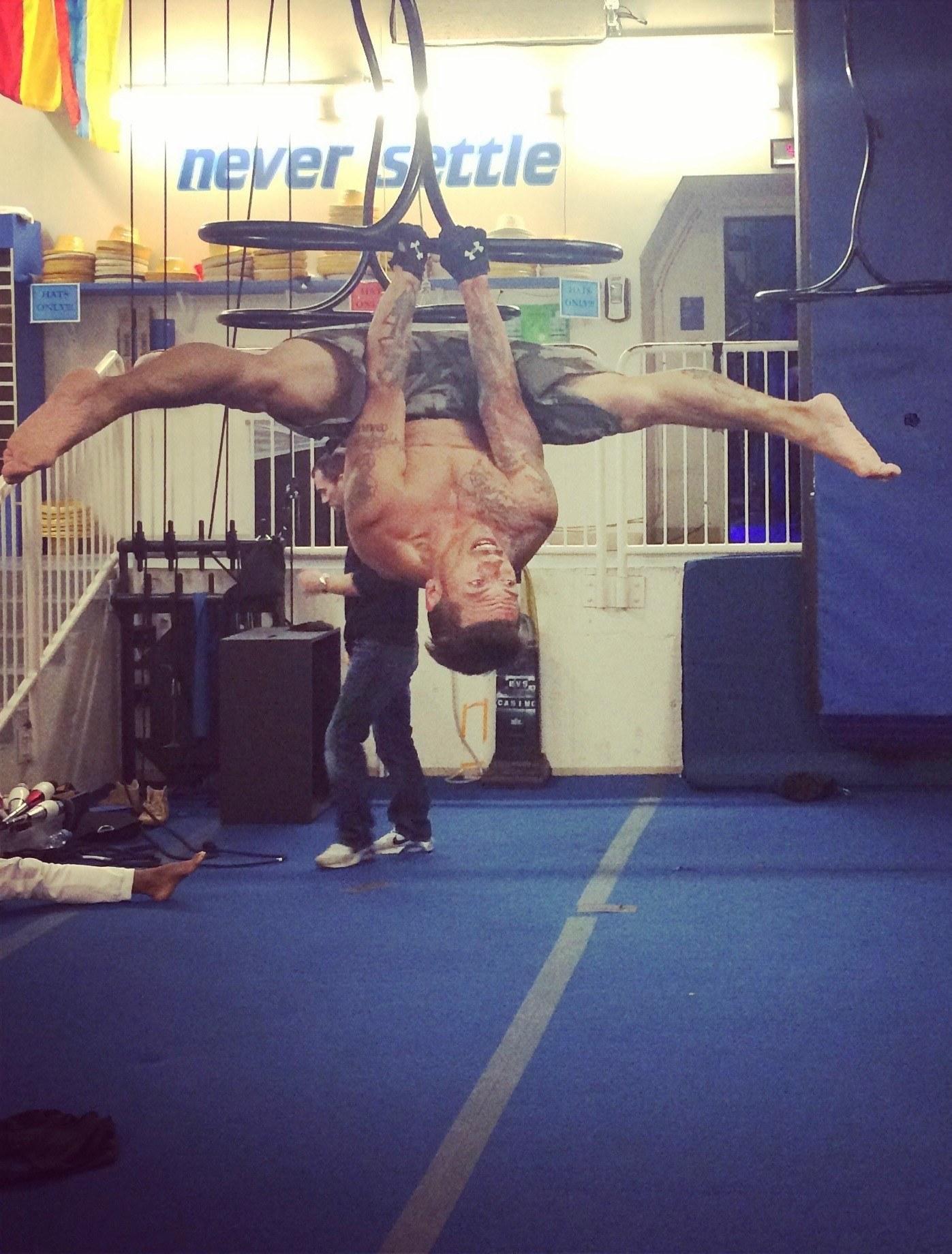 J.J. Villar hanging upside down from aerial straps in a training gym