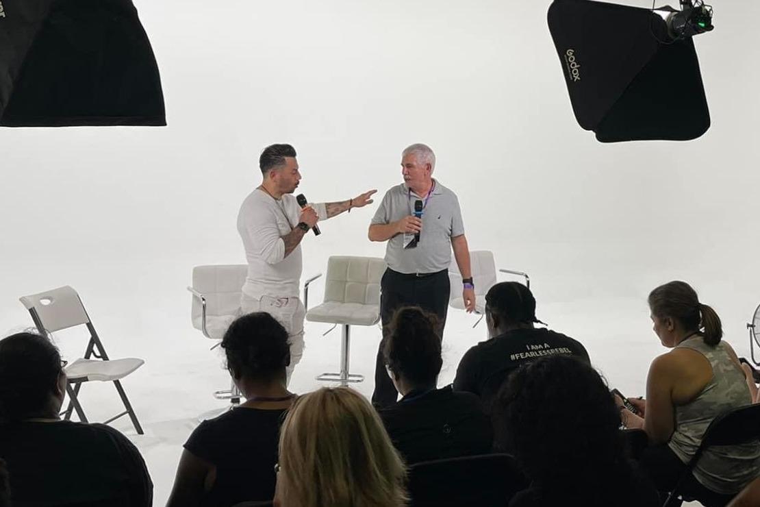 J.J. Villar coaching a participant on a studio stage in front of a seated audience
