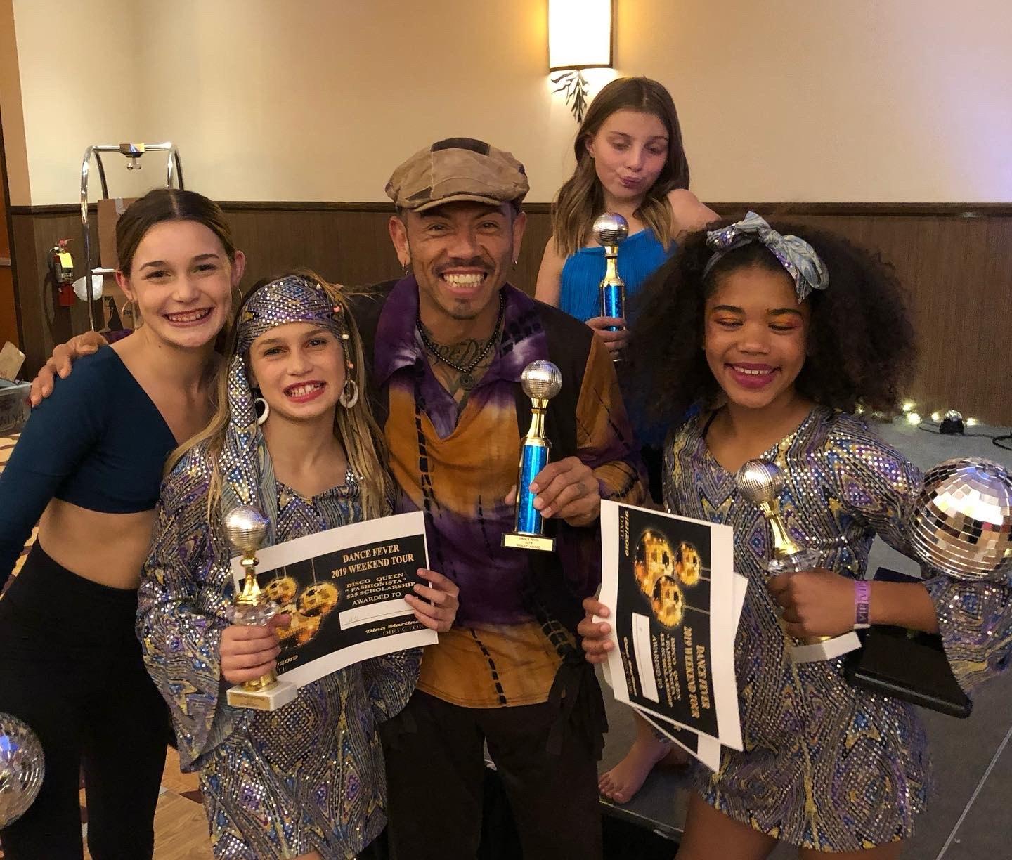 J.J. Villar celebrating with young dancers holding their competition trophies