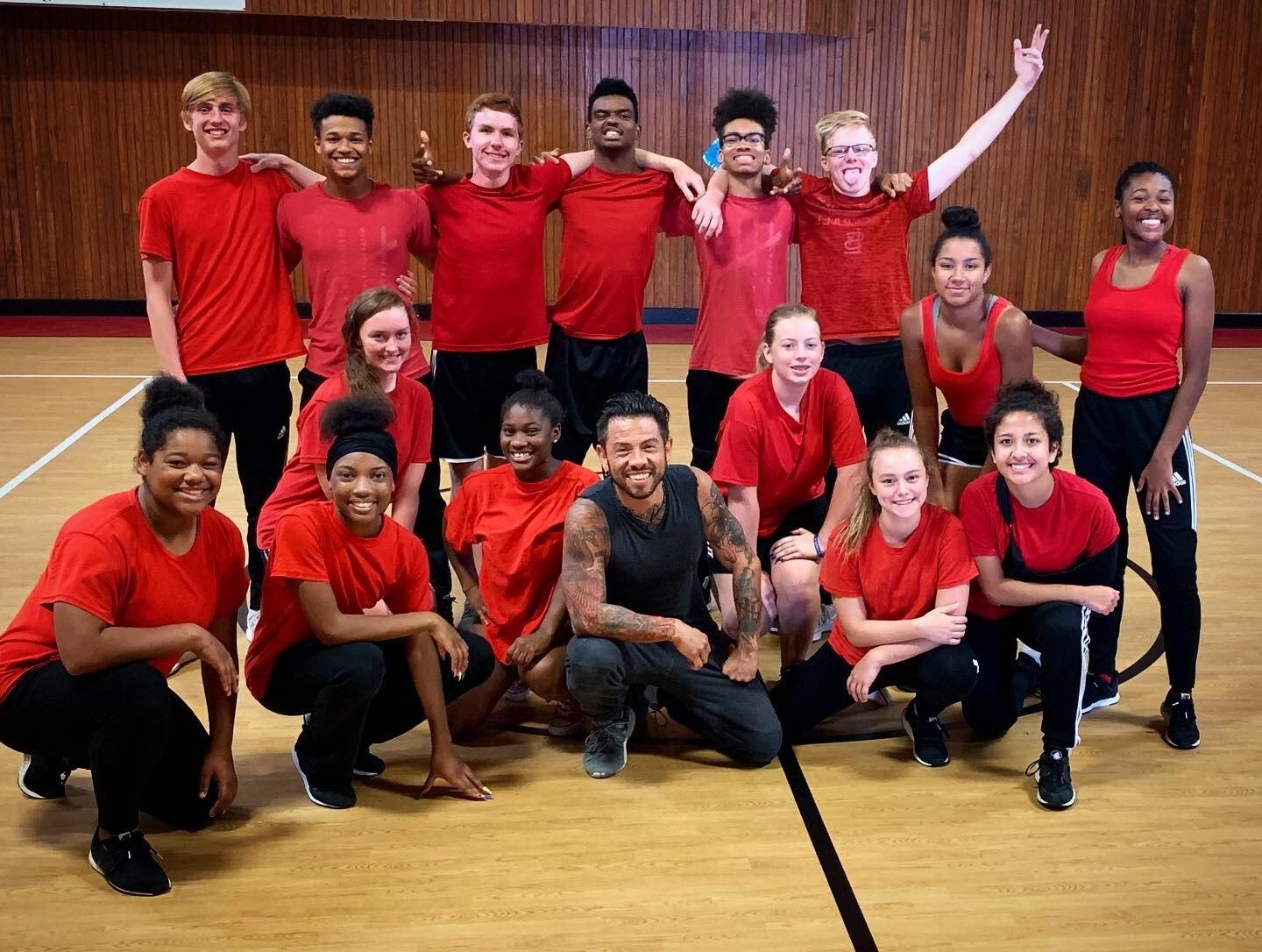 J.J. Villar kneeling in front of a smiling group of student dancers