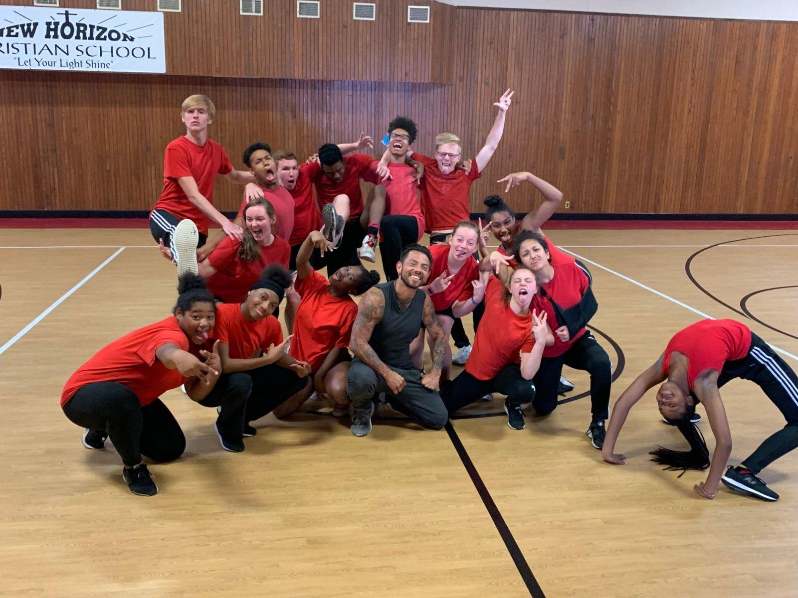 J.J. Villar crouched with a group of student dancers making playful poses