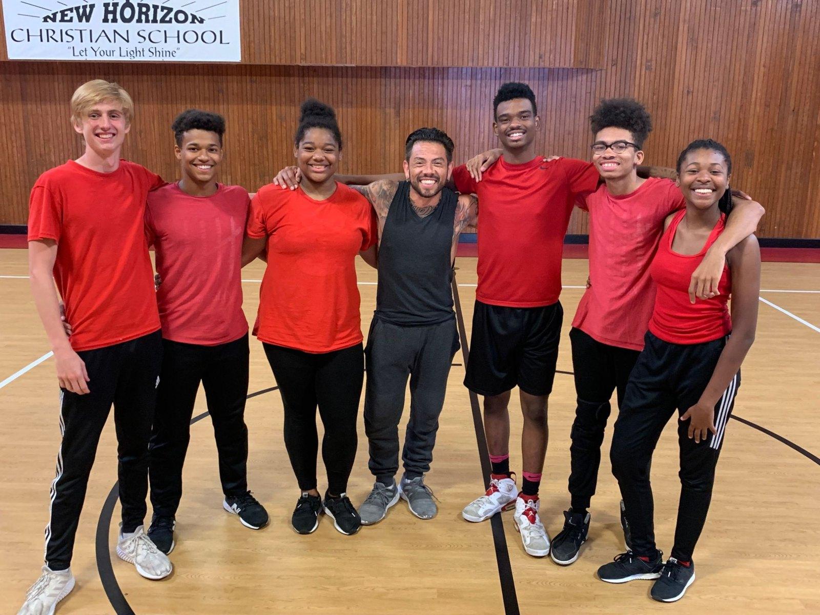 J.J. Villar arm in arm with a team of student dancers in red shirts